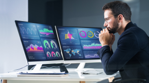 Directeur e-commerce analysant des tableaux de bord GA4 avec données de tracking personnalisé sur double écran